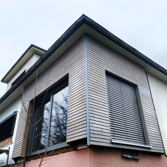 Bardage-d’une-maison-pavillonaire-Bardage-en-mélèze-raboté,-à-clairevoie-27x70,-saturateur-Mauler-pin-grisé-scierie-mandray-bois-de-franche-vosges-2